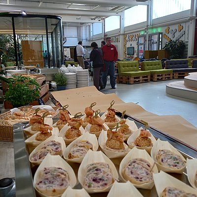 Blick über das Fingerfood des Caterings hinweg in die Veranstaltungshalle hinein.